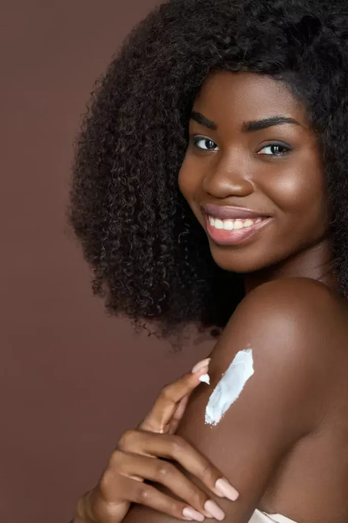 Woman with dark skin tone applying sunscreen